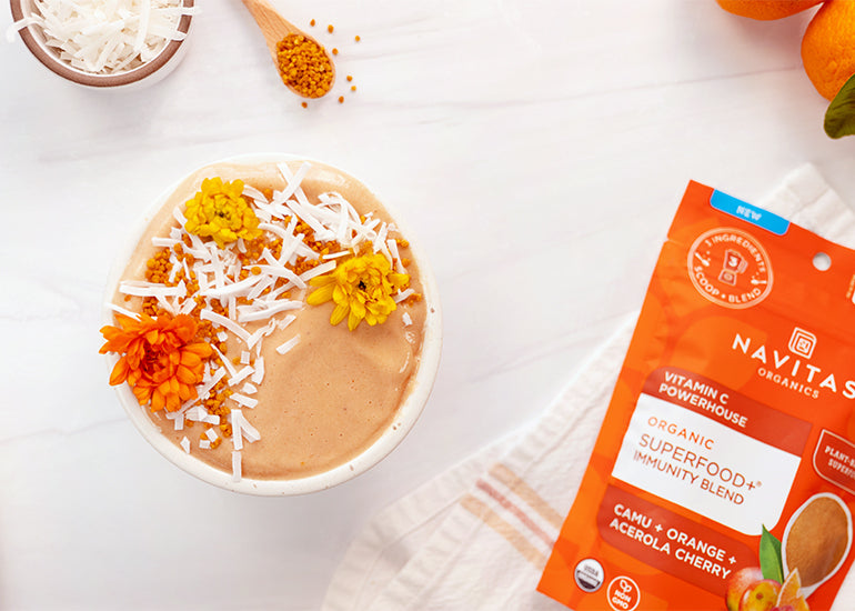 An orange creamsicle smoothie bowl made with Navitas Organics Superfood+ Immunity Blend, topped with shredded coconut and bee pollen.