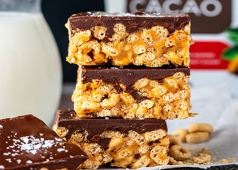A stack of peanut butter cereal treats made with Navitas Organics Maca Powder and Bittersweet Cacao Wafers.