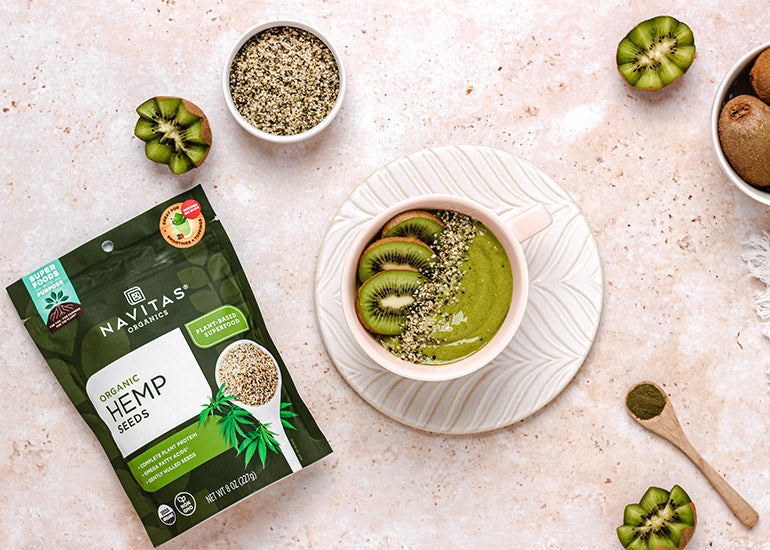 A green kiwi smoothie bowl made with Navitas Organics Superfood+ Greens Blend, topped with Navitas Organics Hemp Seeds and kiwi slices
