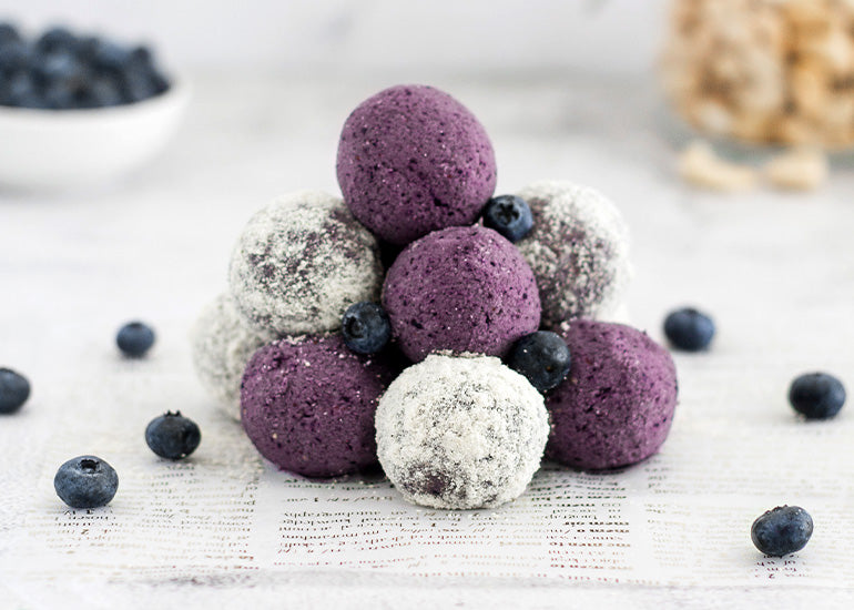 Pile of acai cacao truffles made with Navitas Organics superfoods and sprinkled with blueberries.