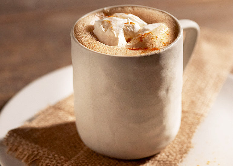 A mug filled with a cacao maca energy elixir made with organic almond milk, Navitas Organics Cacao Powder, Maca Powder and Cacao Butter.