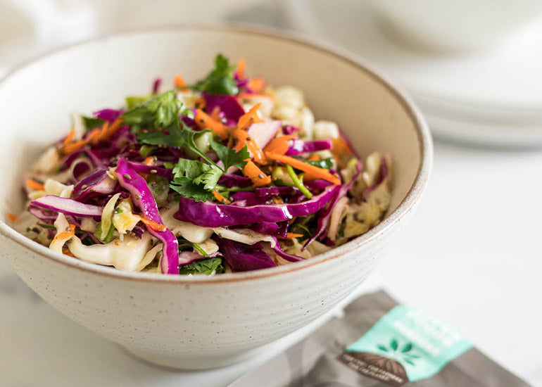 A bowl of coleslaw mixed with a dairy-free dressing made with Navitas Organics Chia Seeds