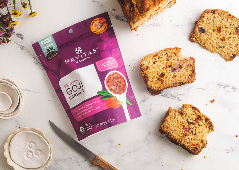 Slices of a cherry goji berry loaf with a bag of Navitas Organics Goji Berries