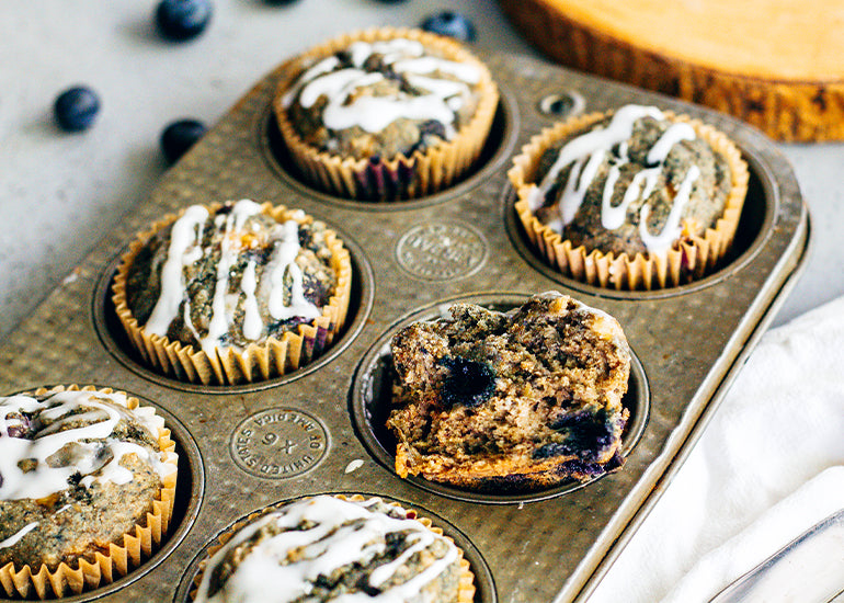 A pan of blueberry banana maqui berry muffins made with Navitas Organics Maqui Powder, drizzled with icing