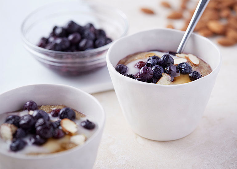 Oatmeal cups mixed with Navitas Organics Maca Powder, topped with fresh blueberries