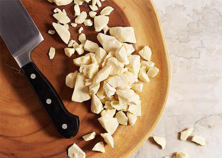 Navitas Organics Cacao Butter, chopped on a cutting board
