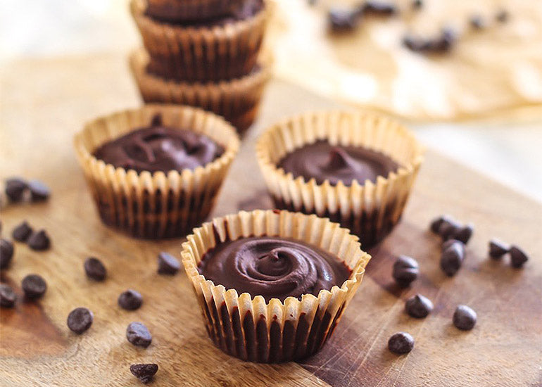 Healthier chocolate peanut butter cups on a cutting board with sprinkles of chocolate chips.