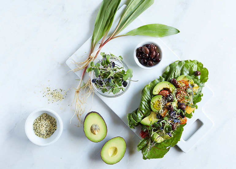 Avocados, plants and vegetables in a lettuce boat on a plate