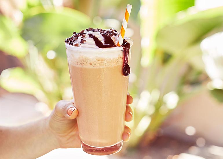 A woman holding a chocolate sauce-topped homemade superfood blended coffee drink