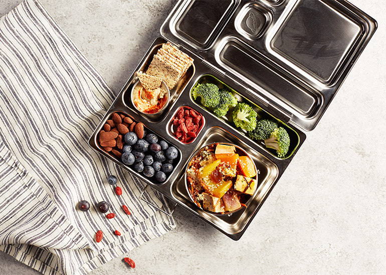 A stainless steel lunchbox filled with healthy foods, including Navitas Organics Goji Berries.