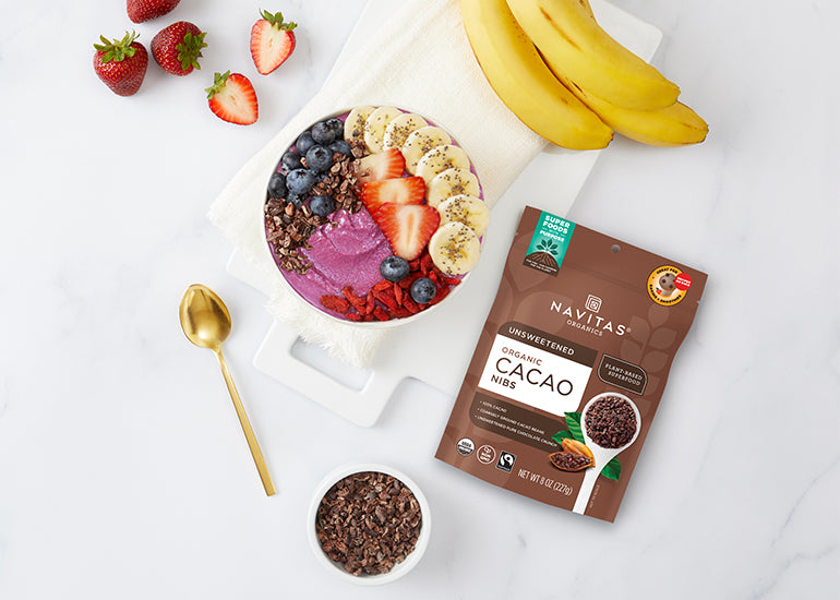A smoothie bowl topped with fresh fruit and Navitas Organics Cacao Nibs