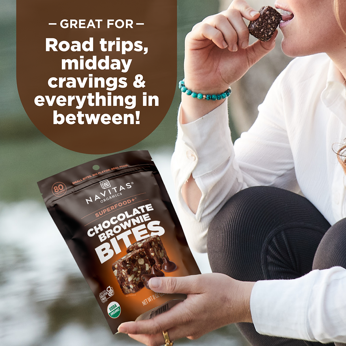 Person holding a package of Navitas Organics Superfood+ Chocolate Brownie BITES with text about its uses.
