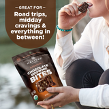 Person holding a package of Navitas Organics Superfood+ Chocolate Brownie BITES with text about its uses.