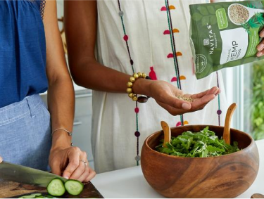A couple pouring Navitas Organics hemp seeds on their salad