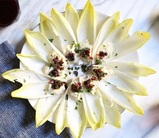 Endive leaves holding turmeric dyed deviled egg filling topped with hemp seeds