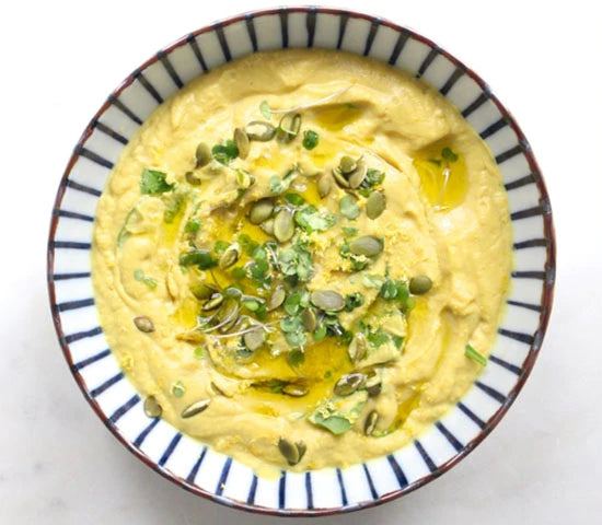 Creamy bowl of cauliflower and turmeric soup topped with hemp seeds and microgreens