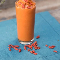 Tall glass of a frosty cacao smoothie with goji berries sprinkled around