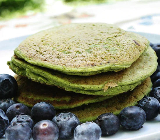 Stack of pancakes made with greens powder surrounded by blueberries