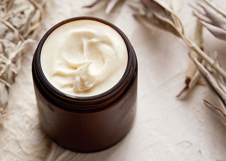 Whipped body butter made with Navitas Organics Cacao Butter in a jar surrounded by sage leaves