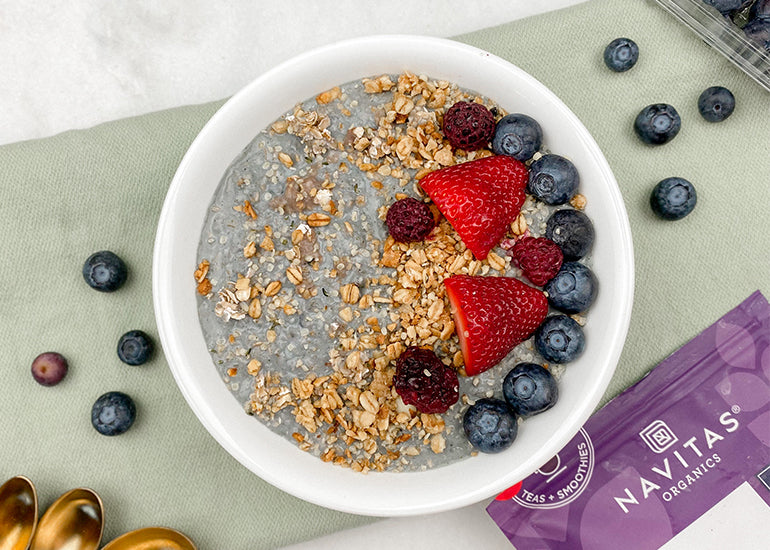 A bowl of oats made with Navitas Organics Elderberry Powder, topped with granola and fresh berries