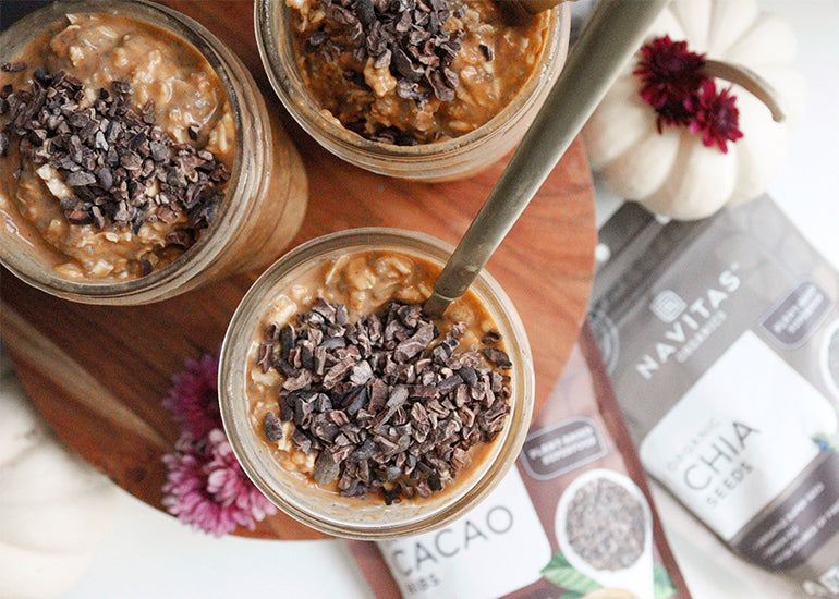 Three mason jars filled with overnight oats made with Navitas Organics Chia Seeds and pumpkin puree, topped with Navitas Organics Cacao Nibs