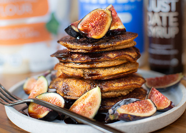 A stack of pancakes made with Navitas Organics Grain-Free Flour, topped with date syrup and fresh sliced figs