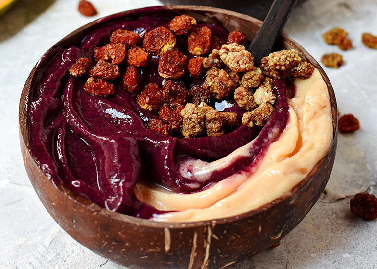 A dark purple and orange swirled smoothie bowl made with Navitas Organics Superfood+ Immunity Blend and Acai Powder, topped with Navitas Organics Mulberries and Goldenberries