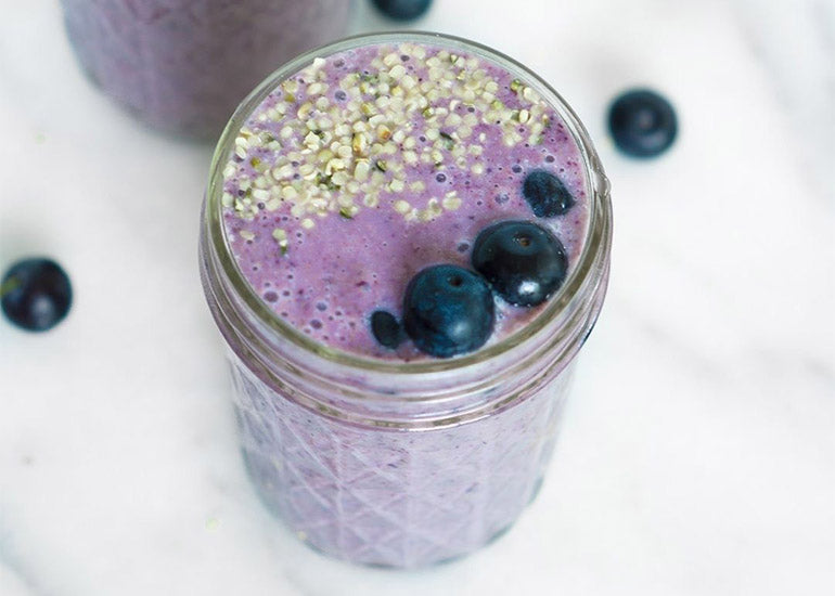 A mason jar filled with a smoothie made with Navitas Organics Hemp Powder, topped with fresh blueberries and Navitas Organics Hemp Seeds