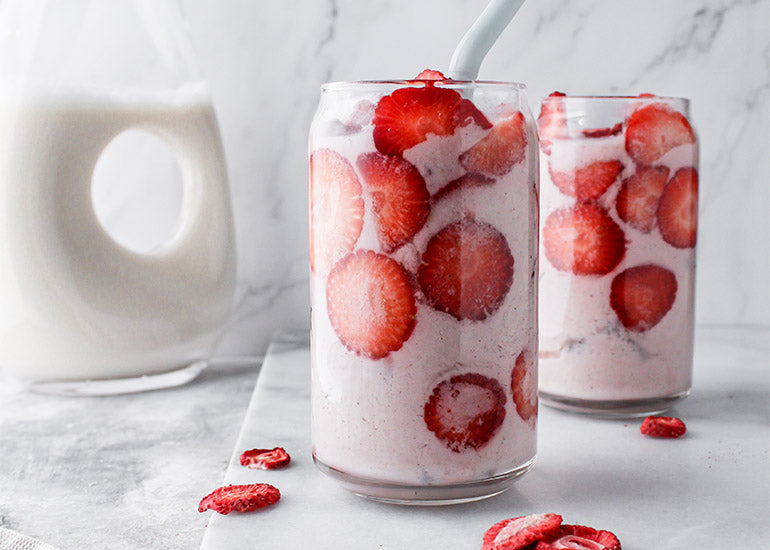 Two tall glasses filled with pink smoothies made with Navitas Organics Acai Powder and strawberries