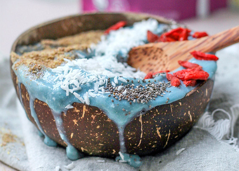 A blue smoothie bowl made with Navitas Organics Superfood+ Adaptogen Blend, topped with ground flax seeds, coconut flakes, and Navitas Organics Goji Berries and Chia Seeds