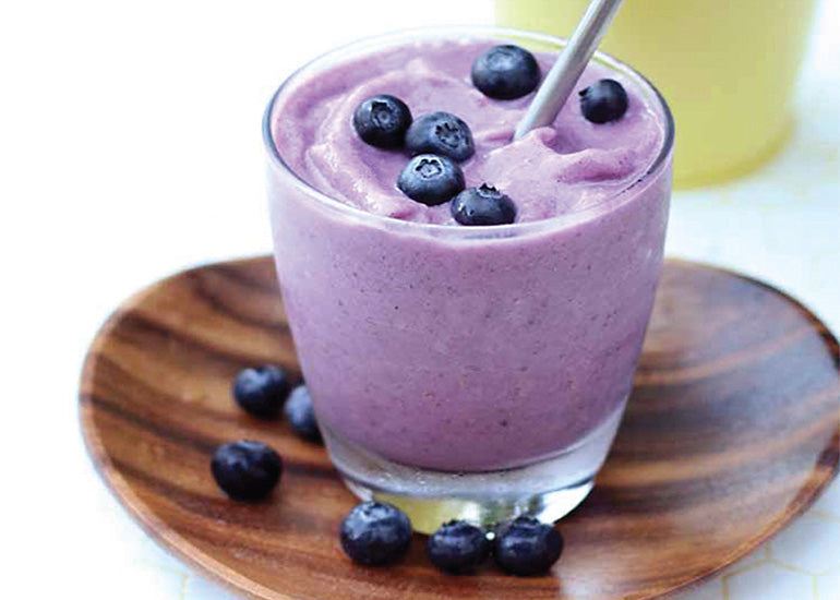 A glass filled with a purple smoothie made with Navitas Organics Maqui Powder and Chia Seeds, topped with fresh blueberries