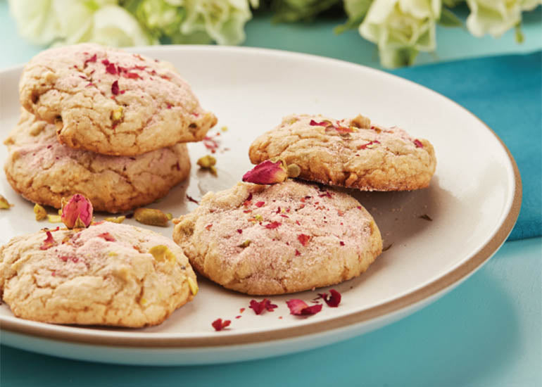 A plate of rose tea cookies made with Navitas Organics Pomegranate Powder and Cacao Nibs, garnished with dried rose petals