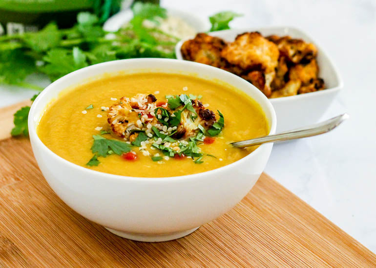 A bowl of hearty cauliflower soup spiced with Navitas Organics Turmeric Powder, garnished with Navitas Organics Hemp Seeds and roasted cauliflower florets