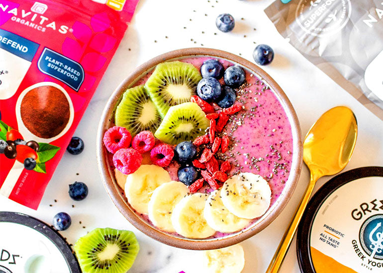 A pink smoothie bowl made with Navitas Organics Superfood+ Berry Blend and Chia Seeds, topped with fresh fruit, goji berries and chia seeds