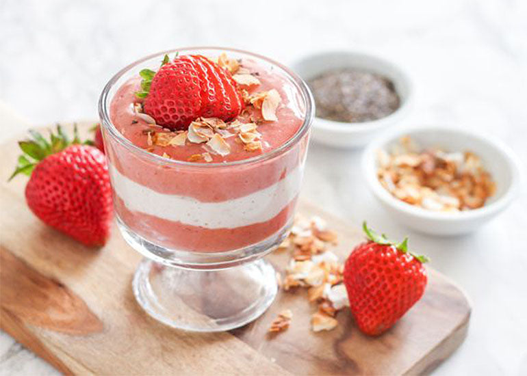 A layered strawberry coconut chia parfait made with Navitas Organics Chia Seeds in a parfait glass, topped with fresh strawberries and toasted coconut.