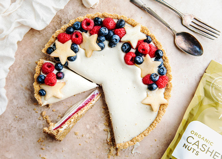 A sliced strawberry cheesecake tart made with Navitas Organics Cashews, topped with fresh berries and pears.