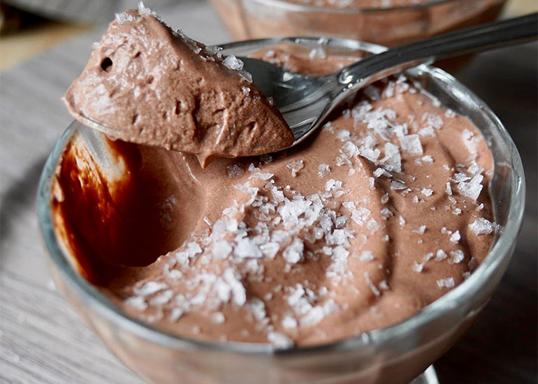 A glass dish filled with chocolate mousse made with Navitas Organics Cacao Powder, sprinkled with Maldon Sea Salt.