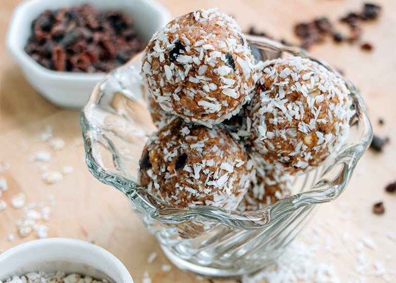 A dish filled with almond cacao energy bites made with Navitas Organics Cacao & Greens Essential Blend and Cacao Nibs.