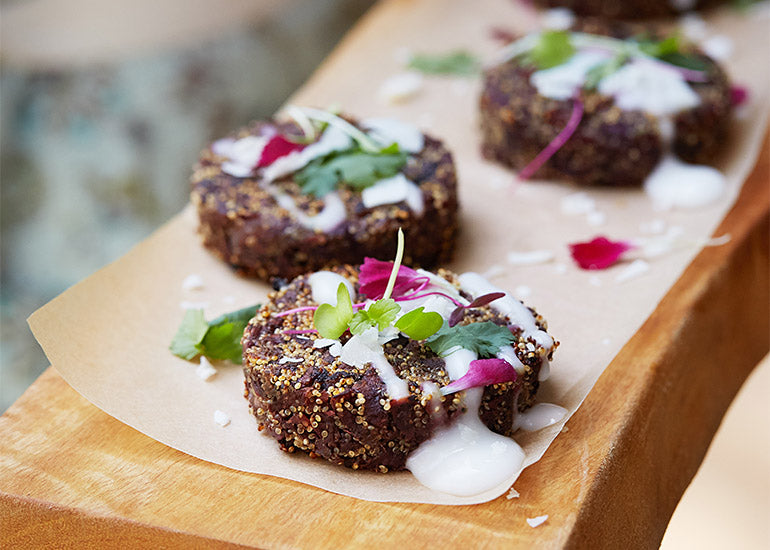 Amaranth and purple yam croquettes made with Navitas Organics Maca Powder and Chia Seed Powder, served on a wooden board.