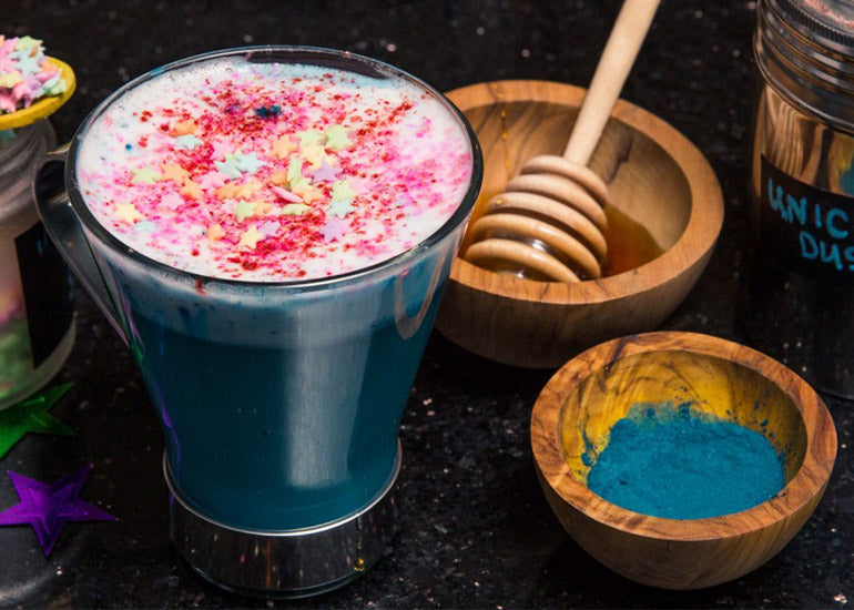 A blue spirulina latte drink made with Navitas Organics Cashew Nuts and Maca Powder, topped with foam and sprinkles.