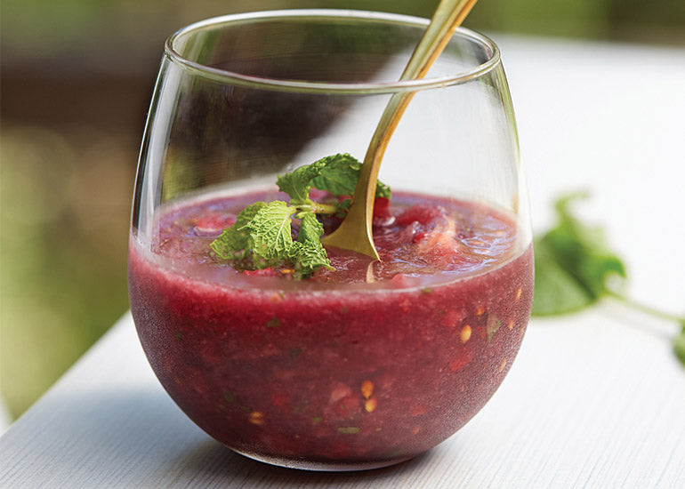 A glass filled with a berry melon slushie made with Navitas Organics Maqui Powder, topped with fresh mint leaves.
