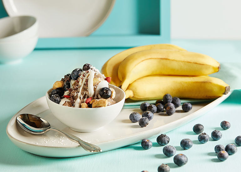 A bowl filled with healthy ice cream made with Navitas Organics Vanilla & Greens Essential Blend, topped with Navitas Organics Goji Berries, Cacao Nibs and Cashew Nuts.