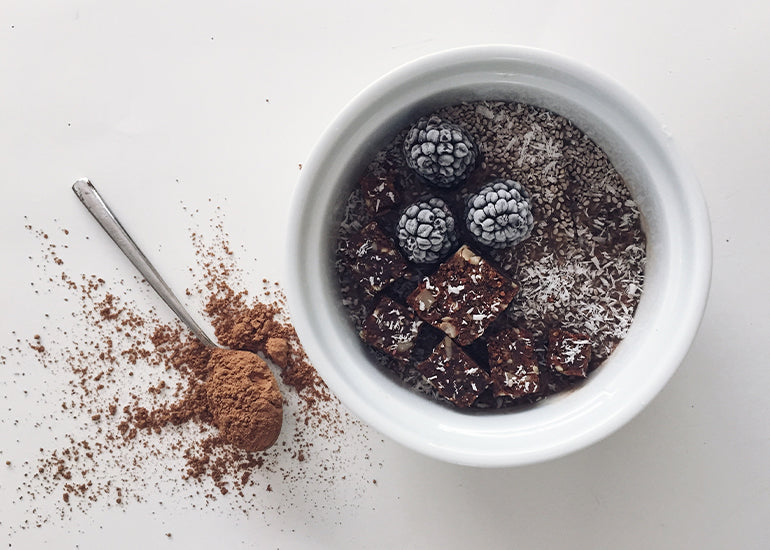 A bowl full of cacao coffee coconut mousse made with Navitas Organics Cacao Powder, topped with Navitas Organics Chocolate Cacao Power Snacks and Chia Seeds
