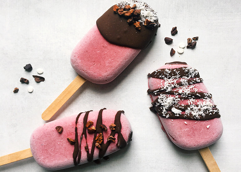 Three frozen strawberry pops drizzled with chocolate sauce made with Navitas Organics Cacao Powder and sprinkled with Navitas Organics Cacao Nibs.