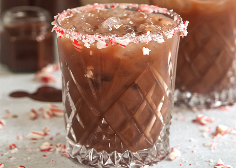 A glass filled with a cacao mint cocktail made with Navitas Organics Cacao Powder, garnished with crushed candy cane pieces