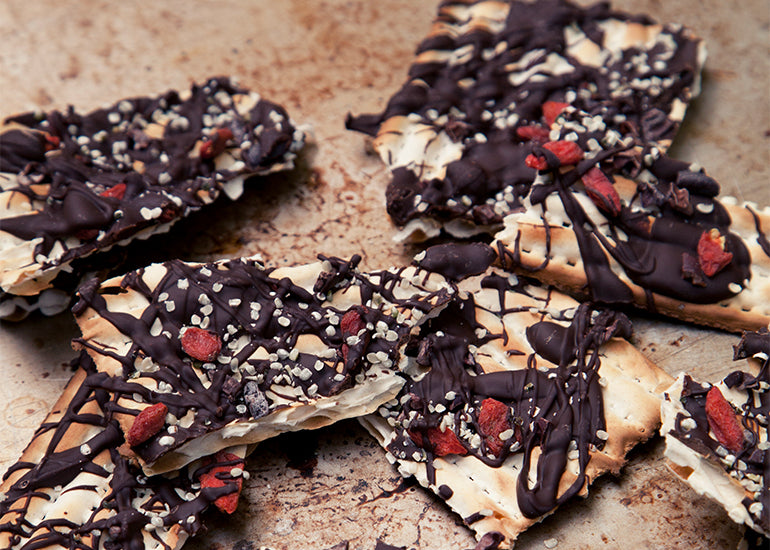 A pile of chocolate matzo crisps made with Navitas Organics Hemp Seeds, Cacao Nibs and Goji Berries.