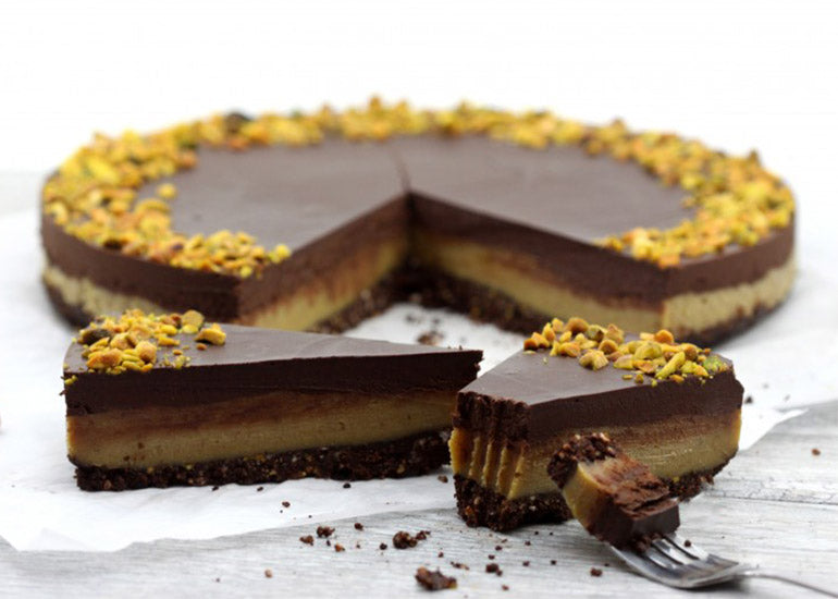 A chocolate pistachio tart made with Navitas Organics Cacao Powder and Cacao Nibs with two slices cut out.