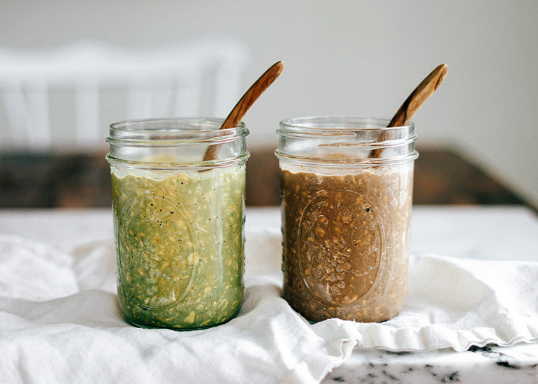 Two mason jars filled with overnight oats made with Navitas Organics Cacao & Greens Essential Blend Protein Powder and Cacao Powder.