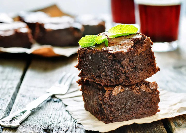 A stack of gluten-free, dairy-free chocolate brownies made with Navitas Organics Cacao Powder, topped with mint leaves.