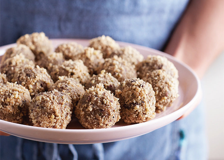 A woman holding a plate topped with maca balls made with Navitas Organics Gelatinized Maca Powder.